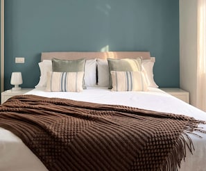 Ein ordentlich bezogenes Bett mit brauner Decke, einem Kopfteil und Kissen mit Streifenmuster.