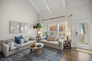 A living room with two sofas, a coffee table, and a large window with blinds. - Enjoy our beautifully renovated Gulf-view condo in West PCB! (Panama City Beach)