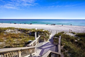 A beach with a wooden boardwalk leading to the shore, clear blue sky, and calm sea. - Princess of Monaco (Miramar Beach)