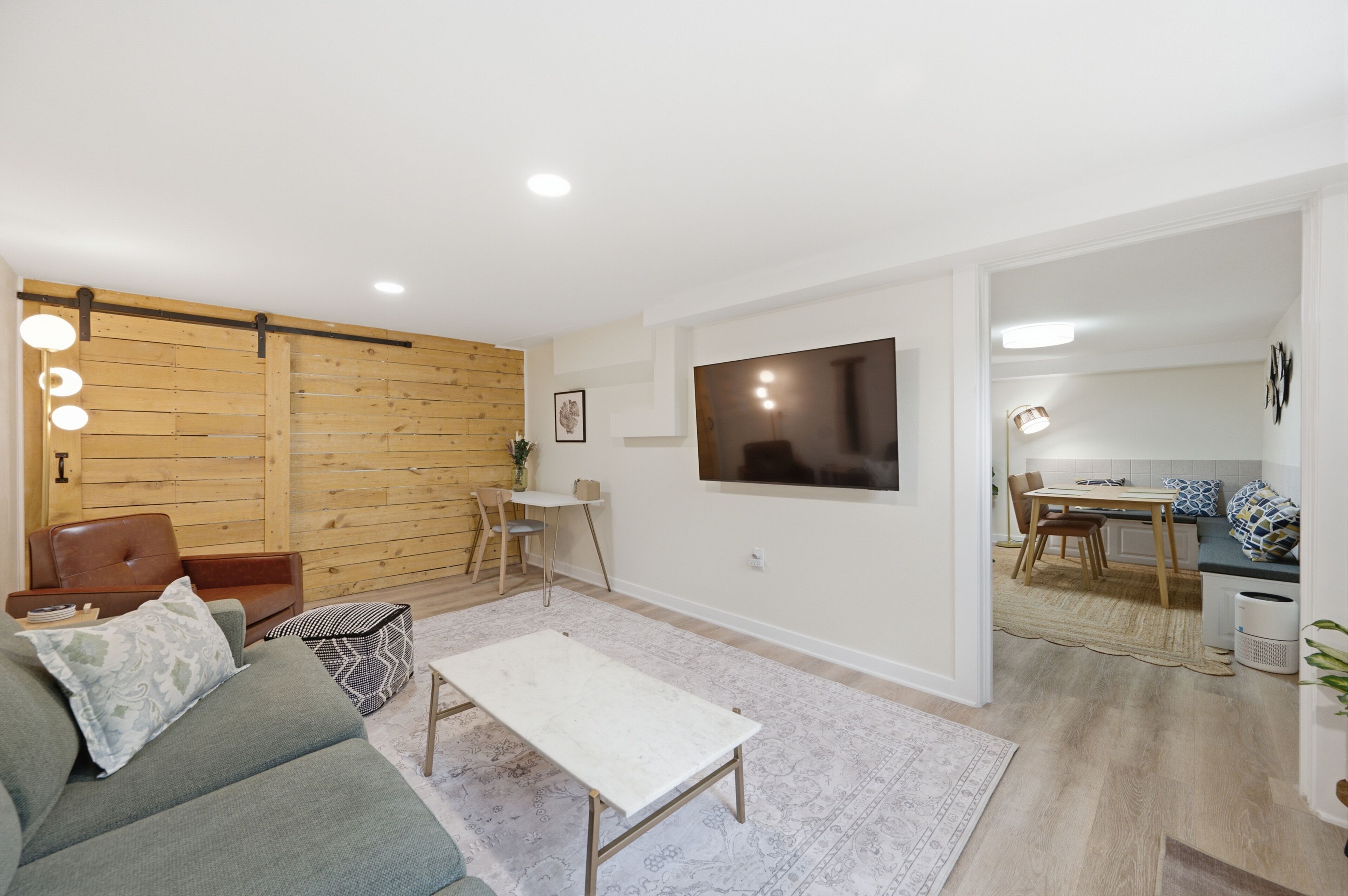 Ein Wohnzimmer mit einer Couch, einem Couchtisch, einem Fernseher und einer Holzwand.