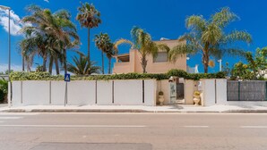 A modern building with a flat roof, a gated entrance, and a clear blue sky.