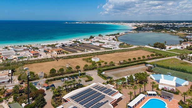 An aerial view of a coastal area with a large body of water, buildings, and a swimming pool.