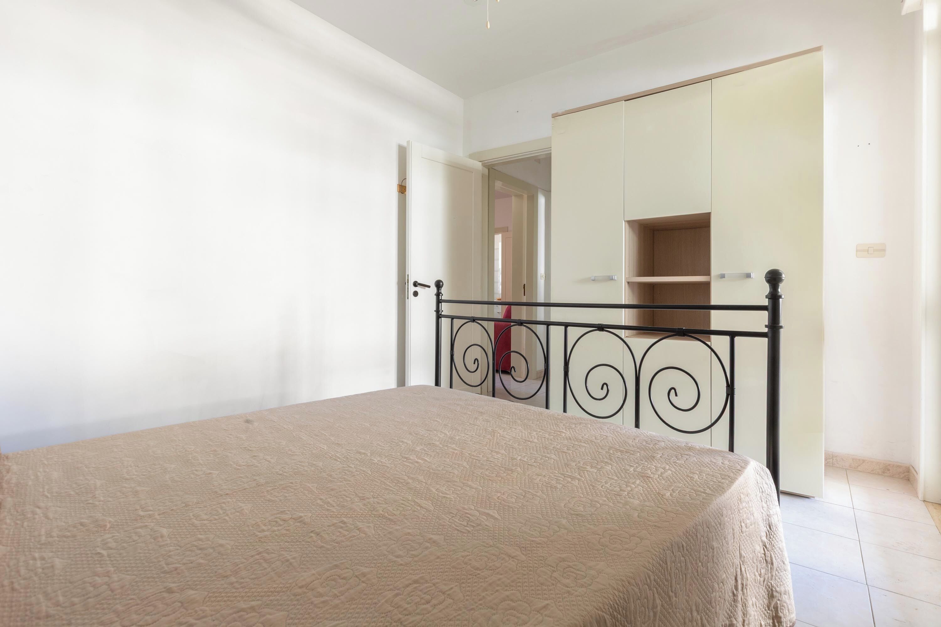 Un dormitorio con cama, armario y puerta que da a otra habitación.