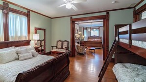A spacious bedroom with a large bed, a chair, a desk, and a staircase leading to another room.