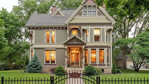 A two-story house with a front porch, a number '310' sign, and a well-maintained lawn.