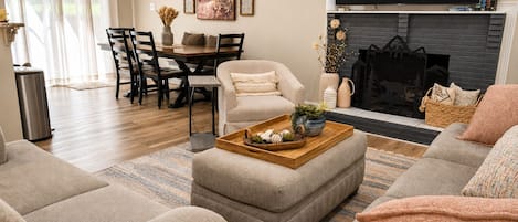A living room with a fireplace, a dining area, and a sofa set.