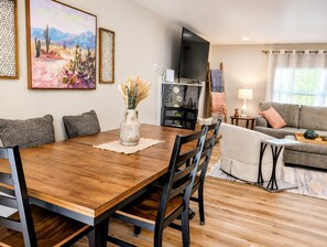 A dining area with a wooden table, chairs, and a vase with dried plants. - Modern Knoxville Retreat/Clean Calm Comfort Family or Work/ Near UT & Downtown (Knoxville)