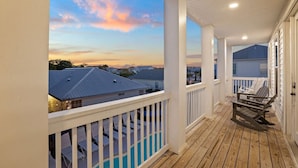 A covered balcony with a view of houses and a sunset. - Sealah @ Crystal Beach (Destin)