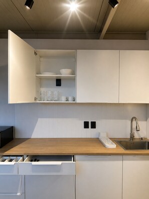 Eine moderne Küche mit weißen Schränken, einer Holz Arbeitsplatte, einem Edelstahl-Spülbecken und einem eingebauten Geschirrspüler.