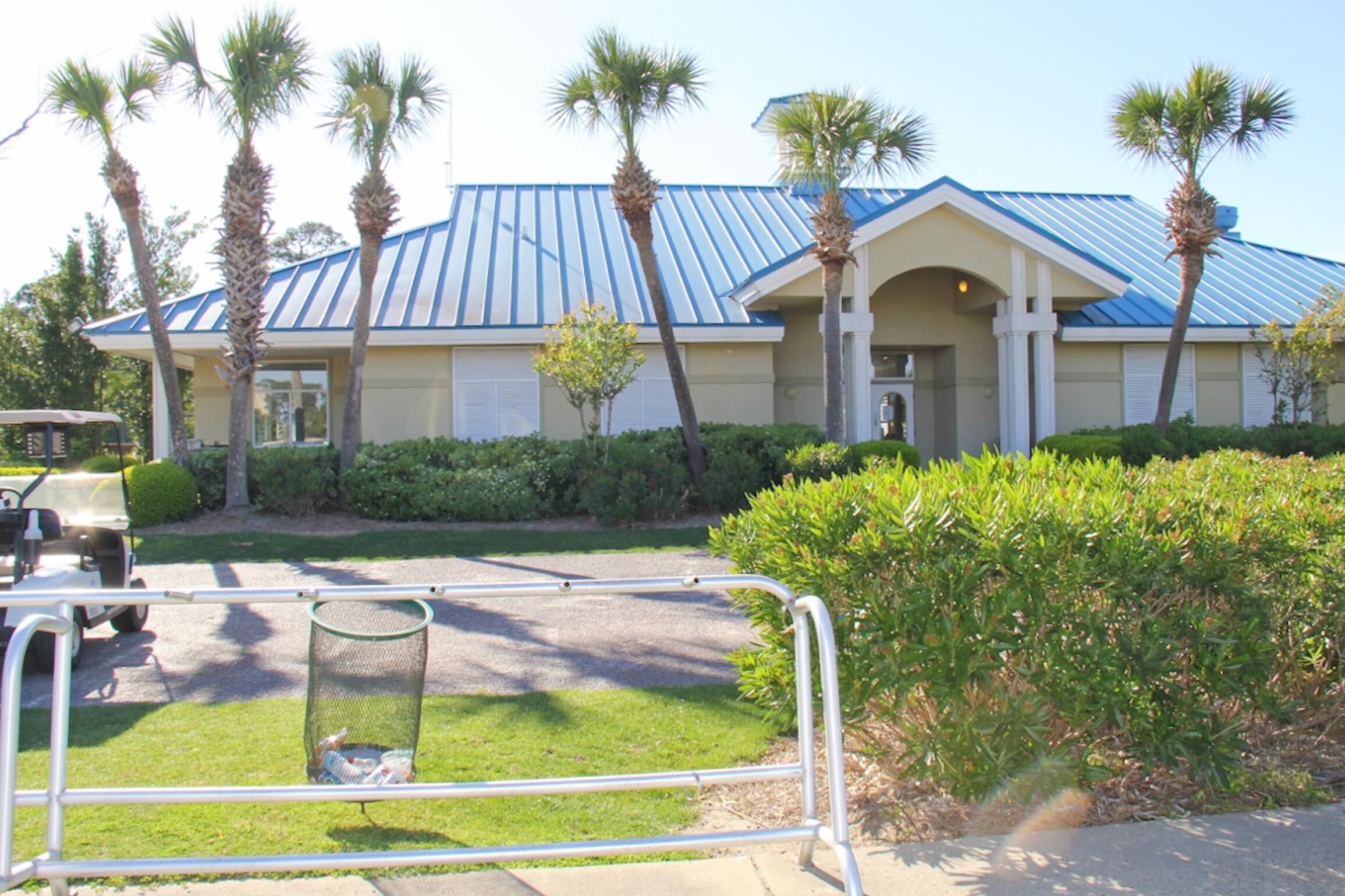 A building with a blue roof and palm trees in the front yard.