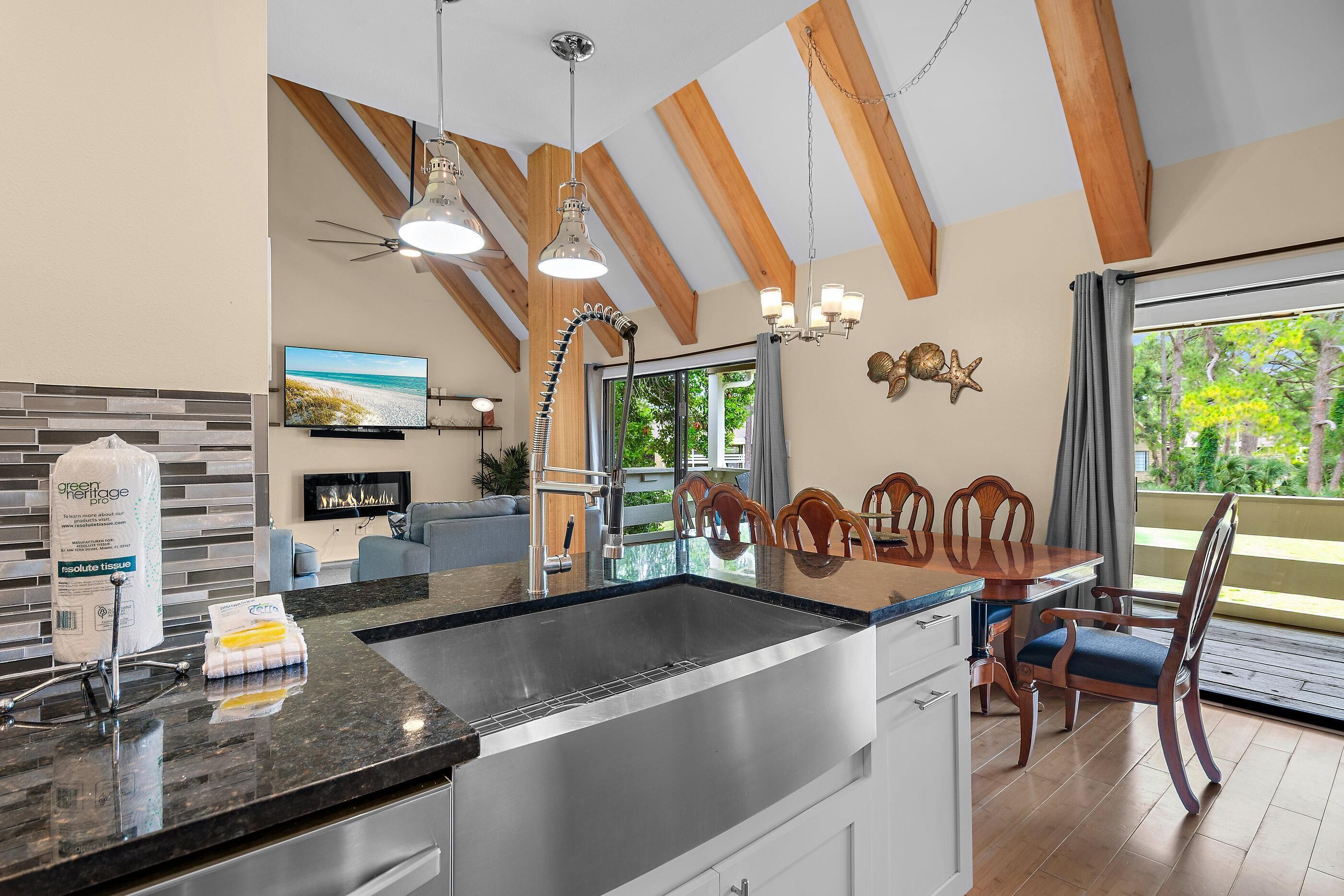 A modern kitchen with a large island, stainless steel appliances, and a dining area with wooden chairs and a table.