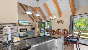 Een moderne keuken met een groot eiland, roestvrijstalen apparatuur en een eethoek met houten stoelen en een tafel.