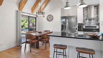 Una cocina moderna con una isla grande, taburetes de bar y un comedor con mesa y sillas de madera.