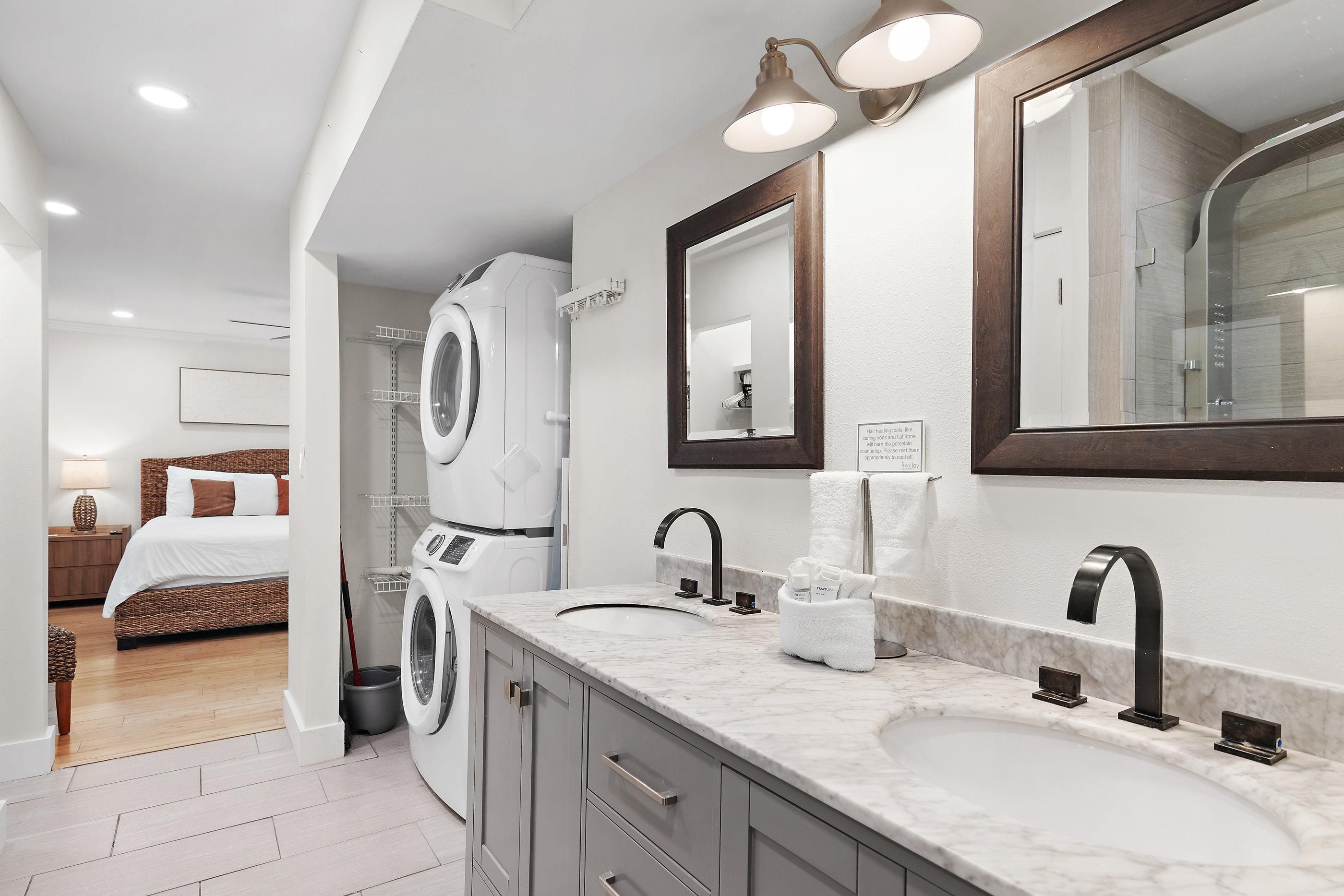 Un baño moderno con lavamanos dobles, un espejo grande y lavadora incorporada.