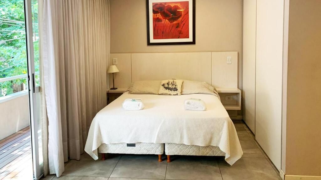 Een hotelkamer met een bed, nachtkastje, lamp en raam met gordijnen.