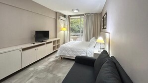 A modern hotel room with a bed, a TV, a sofa, a desk, and a window with curtains. - Marais Recoleta (Buenos Aires)