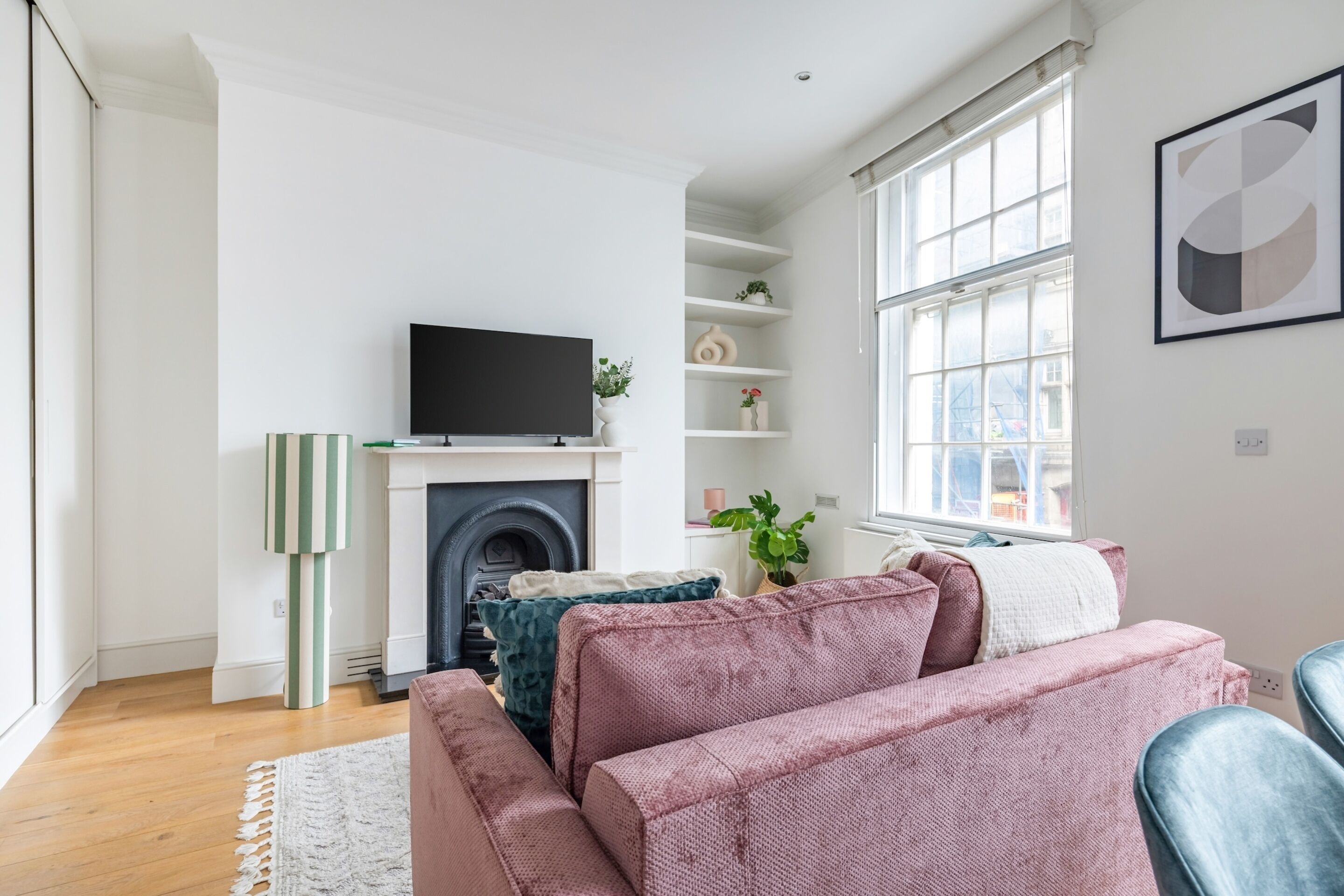 Ein modernes Wohnzimmer mit Kamin, Flachbildfernseher und großem Fenster.