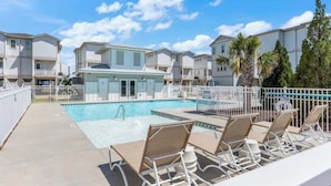 A pool area with lounge chairs, a swimming pool, and multi-story buildings in the background. - The Getaway, just blocks from the ocean. (Carolina Beach)