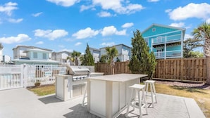 A patio area with a barbecue grill, a bar counter, and outdoor seating. - The Getaway, just blocks from the ocean. (Carolina Beach)
