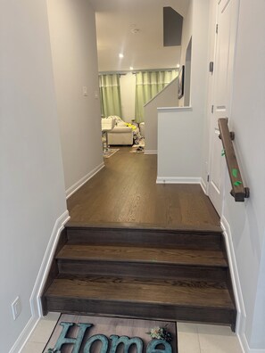 A staircase leading to a living area with a couch and a rug. - Charming One‑Bedroom Getaway in a Peaceful Townhome Setting (Ottawa)