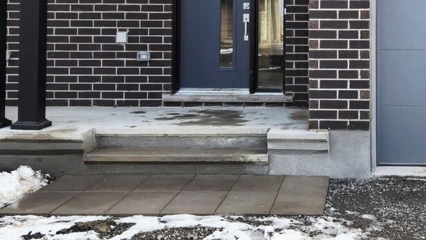 A modern two-story house with a dark brick facade, a red upper section, and a black door. - Charming One‑Bedroom Getaway in a Peaceful Townhome Setting (Ottawa)