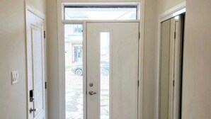 A narrow hallway with a white door at the end, a window above it, and a door on the left. - Charming One‑Bedroom Getaway in a Peaceful Townhome Setting (Ottawa)