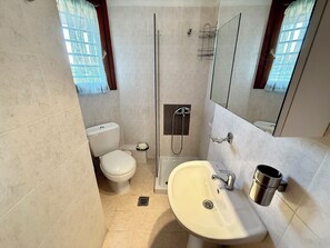 Ein Badezimmer mit Toilette, Dusche, Waschbecken und Spiegel.