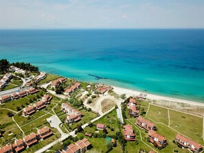 Eine Luftaufnahme einer Küstenwohngegend mit Häusern, einem Strand und freiem Blick auf den Ozean.