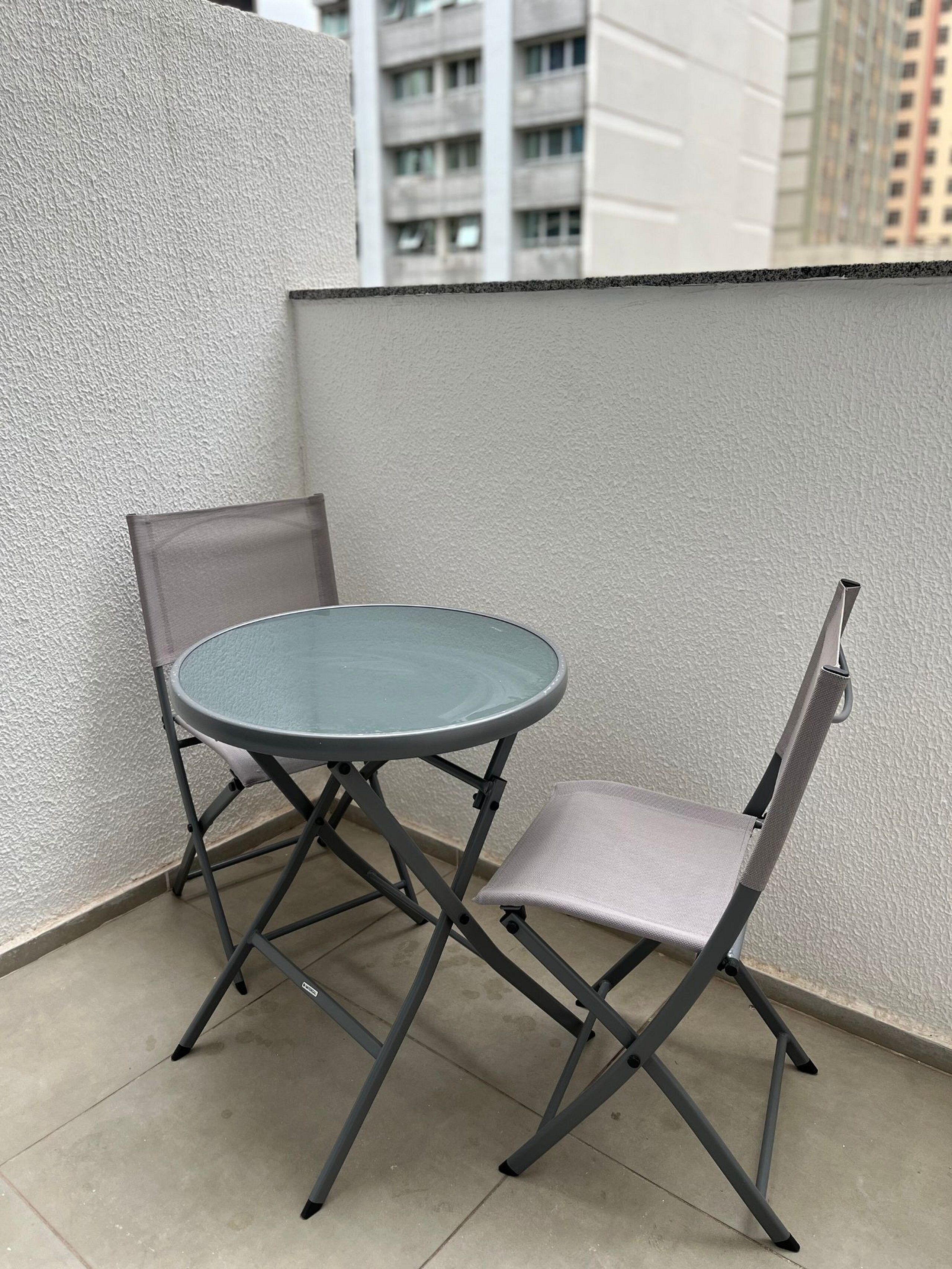 A small outdoor balcony with a round table and two chairs.