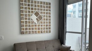 Una sala de estar moderna con un sofá, un cuadro de pared estampado y un ventanal corredero que da a un espacio al aire libre.