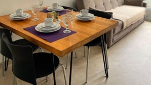 Un comedor con una mesa de madera, sillas negras y un sofá gris al fondo.
