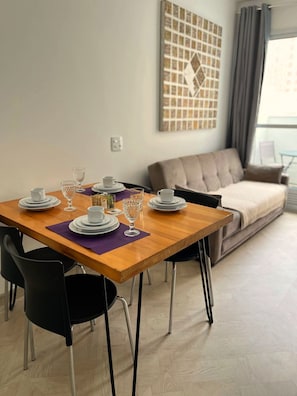 A dining area with a wooden table, black chairs, and a grey sofa in the background. - LK Centro 1 (Belo Horizonte)