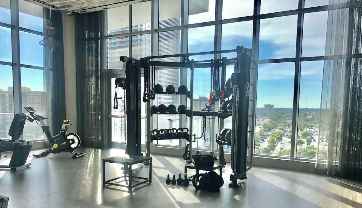 A gym with a squat rack, dumbbells, and an exercise bike.