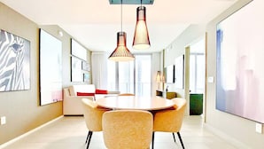 A modern dining area with a round table, four chairs, and pendant lighting. - Stylish Luxury Apartment with Unforgettable Views (Hollywood)