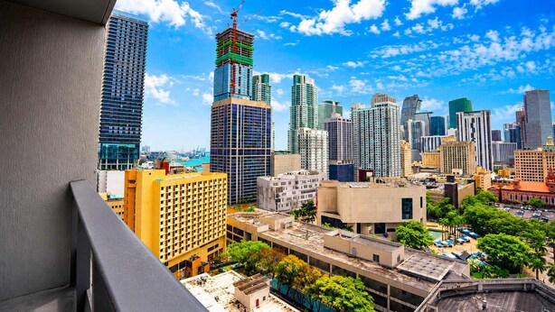 Un paisaje urbano con rascacielos, una grúa de construcción y un cielo azul despejado.