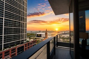 Ein Hochhaus mit Balkon und Blick auf eine städtische Skyline bei Sonnenuntergang.