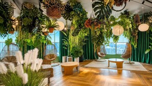 A room with a wooden floor, hanging plants, a round table, and two chairs.