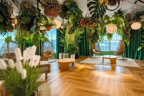 A room with a wooden floor, hanging plants, a round table, and two chairs. - Luxury Downtown Miami Condo for 5 (Miami)