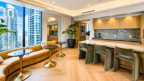 A modern kitchen with a marble backsplash, a built-in bar area, and a seating area with a sofa and round tables. - Luxury Bayview 1BR in Downtown Near Kaseya (Miami)