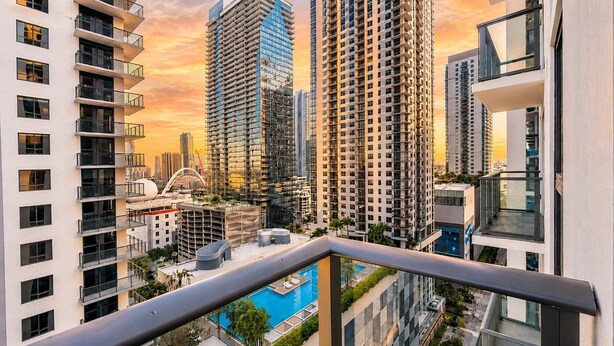 Un edificio alto con molti balconi, una piscina e vista su altri grattacieli.