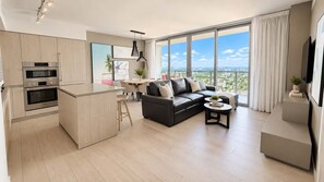 A modern apartment with a kitchen, living area, and a balcony with a city view. - 1 BR Sunset views Hollywood Beach (Hollywood)