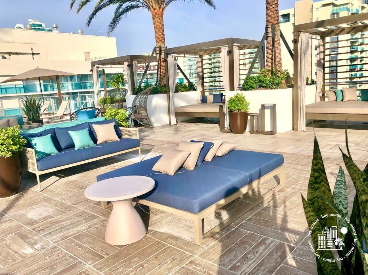 Een terras op het dak met een bank, lounge fauteuils en een tafel.