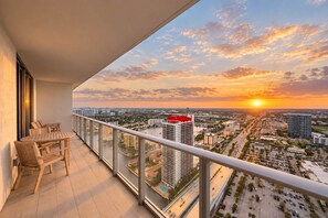 A balcony with a view of a cityscape at sunset, a dining table, and chairs. - 1 BR Sunset views Hollywood Beach (Hollywood)