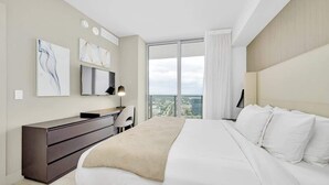 A modern hotel room with a large bed, a desk, and a view of the city. - 1 BR Sunset views Hollywood Beach (Hollywood)