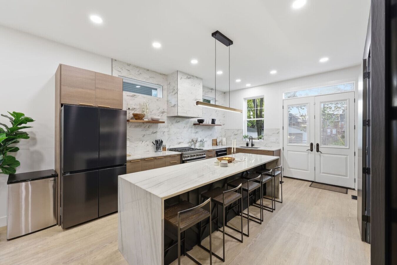 A modern kitchen with a central island, stainless steel appliances, and a large window.