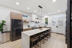 Una cocina moderna con una isla central, electrodomésticos de acero inoxidable y un amplio ventanal.