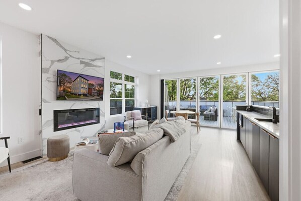 A modern living room with a sofa, TV, and a fireplace. - Linwood House | Rooftop, Hot Tub, Sleeps 15 | (Columbus)