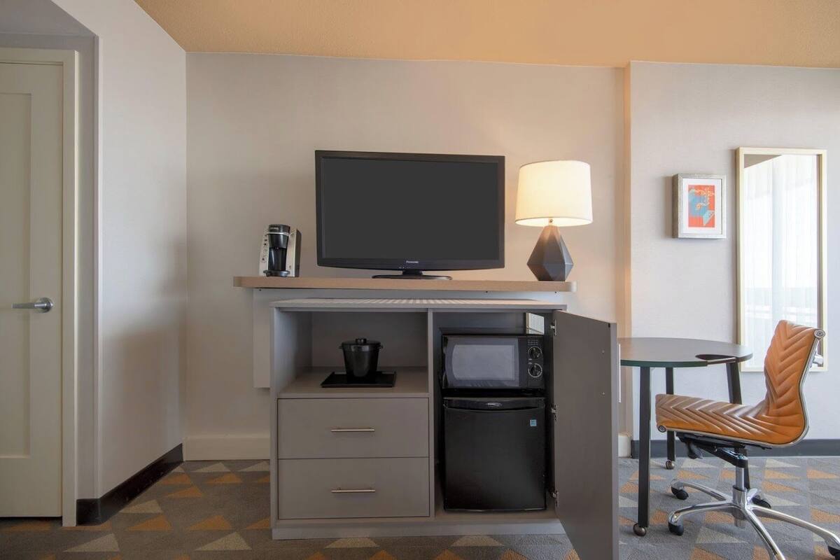 Une chambre d’hôtel équipée d’une télévision, d’une machine à café, d’un four à micro-ondes et d’une chaise.