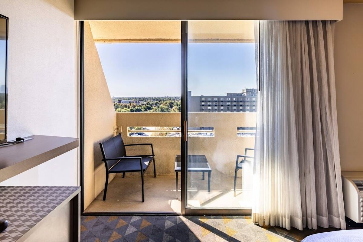 Une chambre d’hôtel avec un balcon, une chaise, une table et un lit.