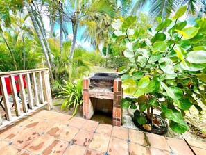 A brick outdoor grill surrounded by lush greenery and a tiled patio. - Villa 15 Flamenco Beachfront Villas (Flamenco)